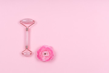 Obraz na płótnie Canvas Jade roller with ranunculus flower on pink drop. Beauty time, selfcare, beauty log, feminine journal concept. Place for text