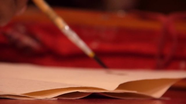 the Lama's hand writes with an ancient Tibetan writing brush