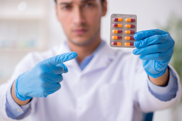 Young male lab assistant in drug synthesis concept