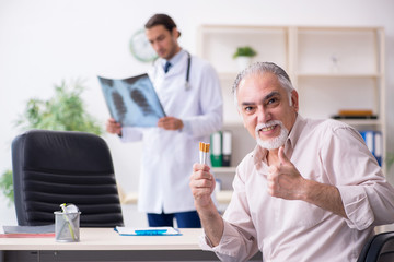 Young male doctor and old patient in antismoking concept