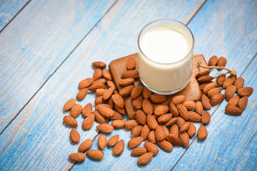 almond milk glass for breakfast health food - almonds nuts on wooden cutting board background