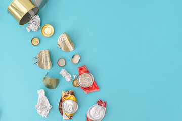 Metal garbage flies out of a metal can on the blue background. Waste separation concept. Flatlay,...