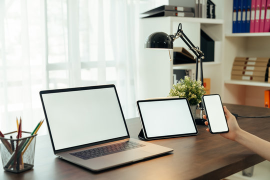 Woman using digital laptop and tablet with smartphone on the table in house. Blank screen for advertising.