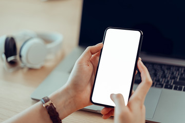Closeup of young woman hand holding smartphone on the table and the screen is blank, social network concept..
