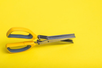 Salad scissors with multiple blades on a yellow background.