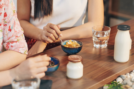 Close-up image of young women having cornflakes and yogurt for breakfast when meeting in cafe