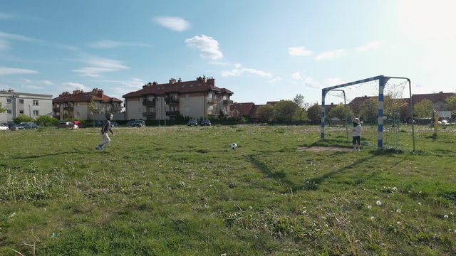 The boy kick the ball into the football goal and does not hit. Children play soccer on the field