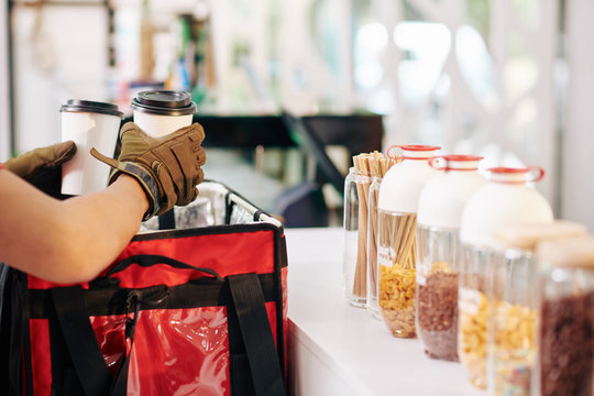 Cropped image of barista putting cups with hot take out coffee in insulated food delivery bag
