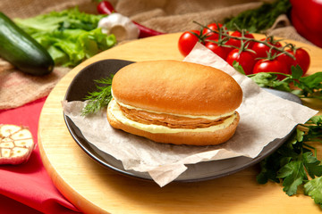 Sandwich with meat, cheese and fresh vegetables, closed, on wooden background