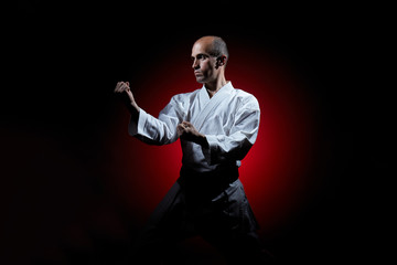 On a red gradient background a young athlete stands in a karate stance