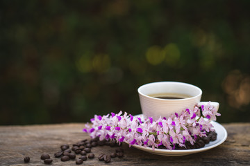 Cup coffee, wild fragrance orchid and roasted coffee bean on wooden table.