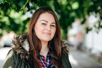 Attractive, pretty woman looking straight into the camera outdoors under a green tree