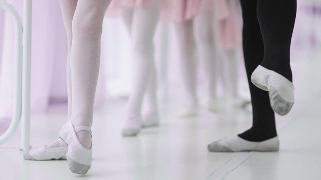 Female legs in ballet shoes students and teacher dancing. Choreography, classical ballet, art and children concept.