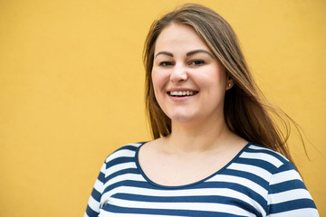 Happy overweighted woman posing isolated over orange background