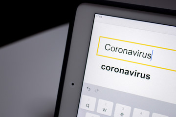 Coronavirus in search bar in search engine on tablet on table.