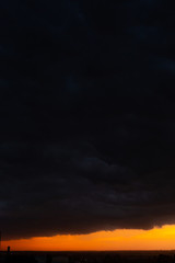 Black thunderclouds at sunset. Bright orange sunset and dark clouds. Storm sky