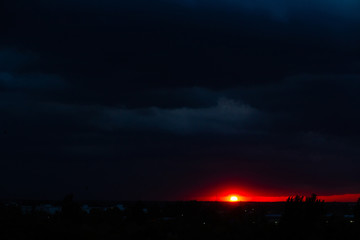 Fototapeta premium Black thunderclouds at sunset. Bright orange sunset and dark clouds. Storm sky