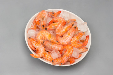 Tiger prawns with ice cubes in a white plate.