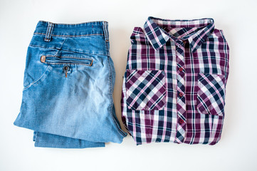 Clothing, folded plaid shirt and jeans on a light background