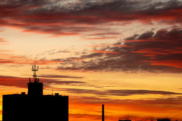 Buildings on a sunset background. Beautiful red sunset with gloomy clouds. The day is ending.