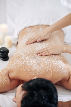 Cosmetologist Giving Young Man Exfoliating Spa Massage With Organic Salt Peeling