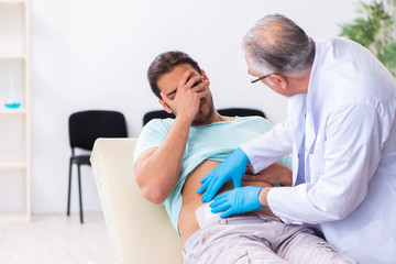 Injured young man visiting experienced male doctor