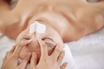 Fototapeta premium Man with nose strip getting anti-aging and refreshing face massage in beauty salon