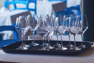 Clean wineglasses on tray in restaurant. Outdoors summer terrace.