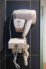 White electric Hair Dryer on black wall in the modern bathroom.