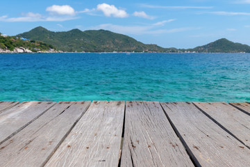 Old wooden platform beside the sea under the blue sky. Wood deck with blue ocean background.