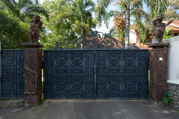 Dark blue iron forged gate in front of the house. Classic ornamental forged metal double gates.