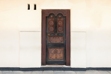 Old black wooden door with gold antique handle and white concrete wall. Details Classic vintage doors of the interior element. Copy space for text.