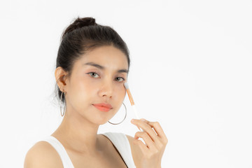 Beauty face of young Asian woman applying make up with brush over white isolated background. Healthy and cosmetics concept.