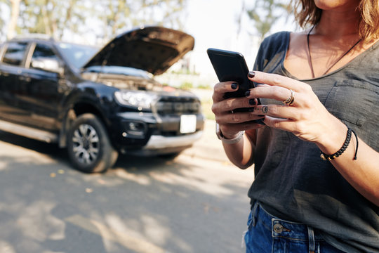 Cropped image of young woman using mobile application to connect car service