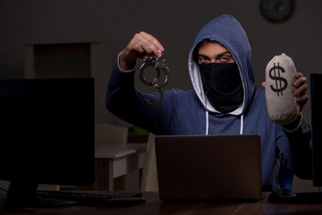 Male hacker hacking security firewall late in office