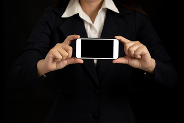 Business woman holding a blank screen smartphone with both hands on black background