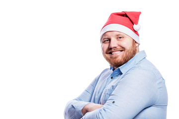 Smiling redhead man in santa claus hat. New Year and Christmas celebration. Isolated on a white background. Space for text.