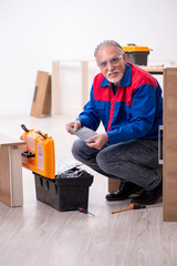 Old male carpenter working indoors