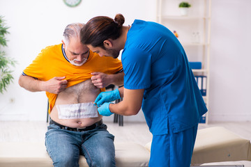 Fototapeta premium Old man visiting young male doctor