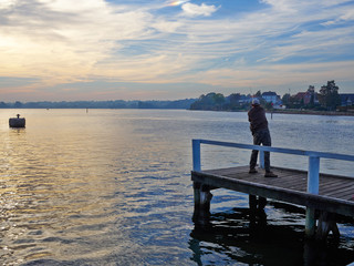 Fototapeta na wymiar Fisherman in action on a wooden pier