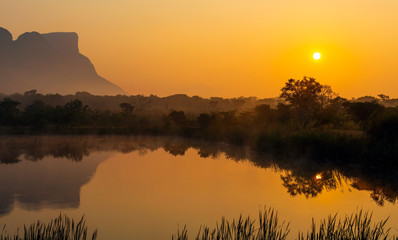 Panorama of Hanging Lip or Hanglip mountain at sunrise in the mist by a swamp lake, Entabeni Safari...
