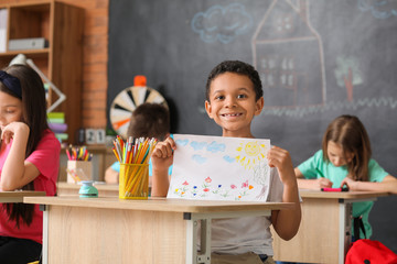 Cute African-American boy with drawing at school