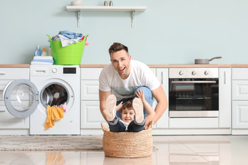 Man and his little son having fun while doing laundry at home