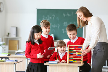 Children with math teacher during lesson in classroom