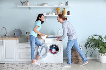 Happy young couple doing laundry at home
