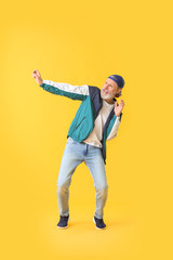Cool senior man dancing against color background