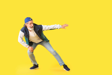 Fototapeta na wymiar Cool senior man dancing against color background