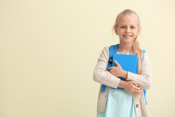 Cute little schoolgirl on color background