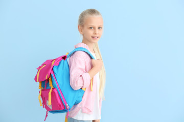 Cute little schoolgirl on color background