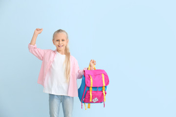 Cute little schoolgirl on color background